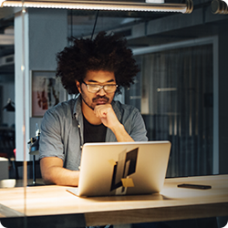 A man with glasses looking at his laptop screen